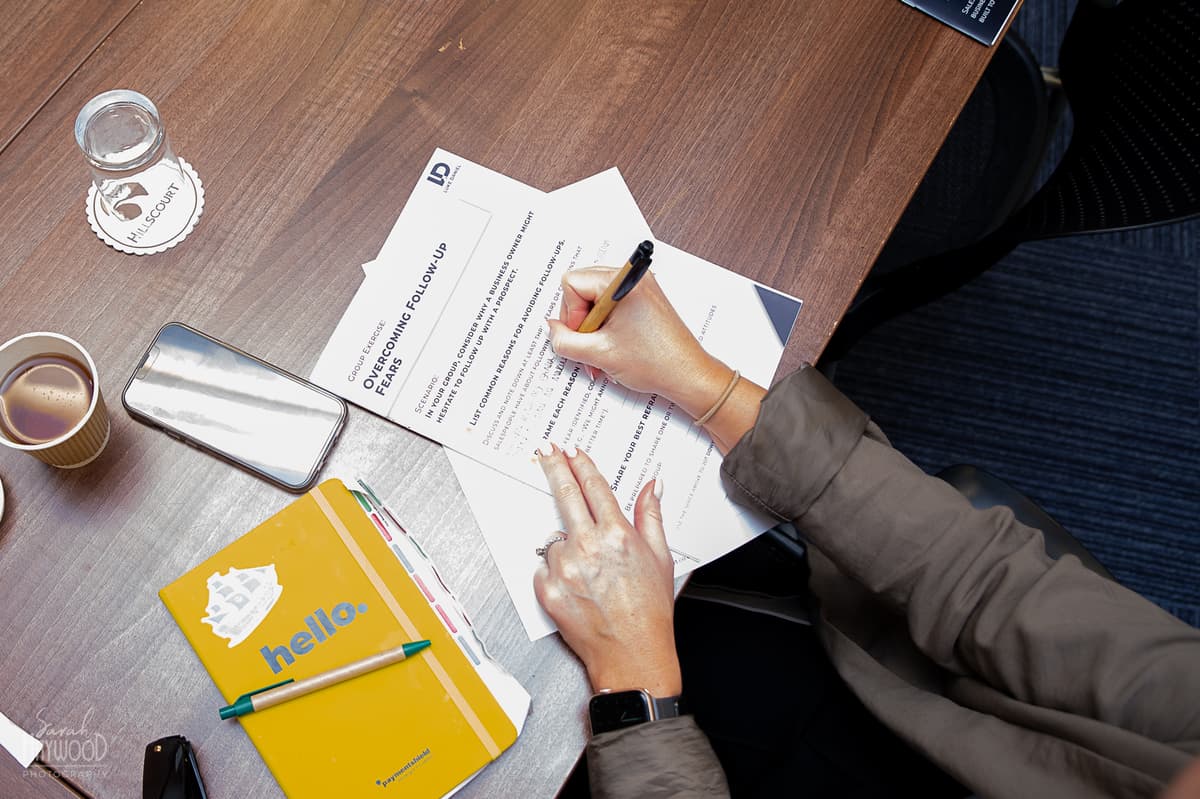 An attendee's hands making handwritten notes during a training session